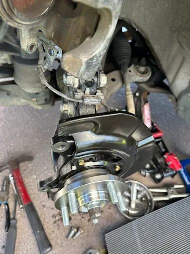 Steering knuckle with a new wheel hub and bearing going onto a car